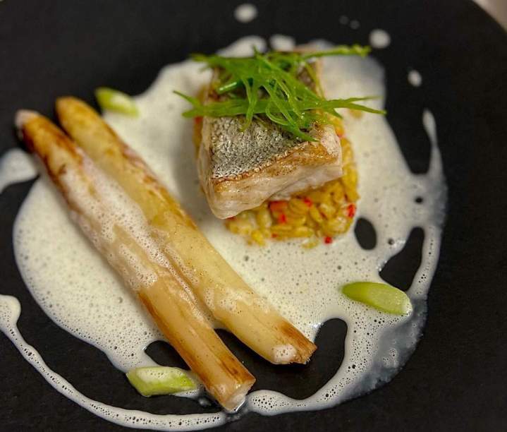 Plat de merlu de ligne servi avec des asperges et une sauce, Fontvieille